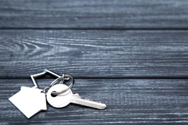 Siyah ahşap masa üzerinde ev sembolü ile gümüş anahtar