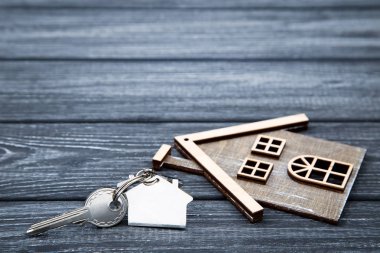 Siyah ahşap masa üzerinde ev sembolü ile gümüş anahtar