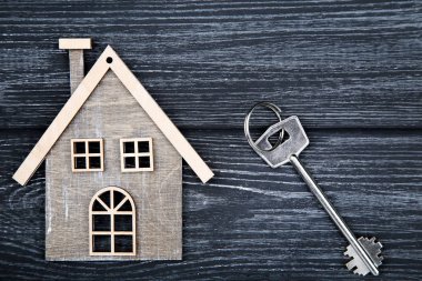 Siyah ahşap masa üzerinde ev sembolü ile gümüş anahtar