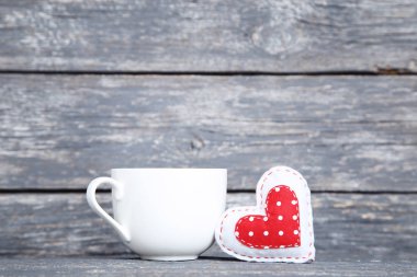 Gri ahşap masa üzerinde beyaz fincan ile Kumaş kalp