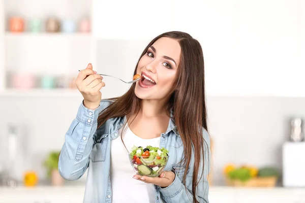 Mulher bonita comendo salada fresca na cozinha — Fotografia de Stock
