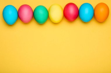 sarı arka plan üzerinde renkli Paskalya yumurtaları