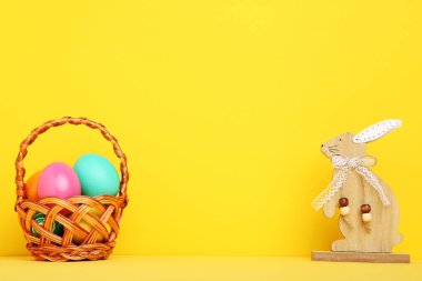 Sarı arka planda ahşap tavşan ile renkli Paskalya yumurtası