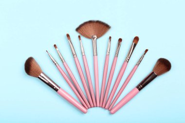 Mavi arka planda makyaj fırçaları seti