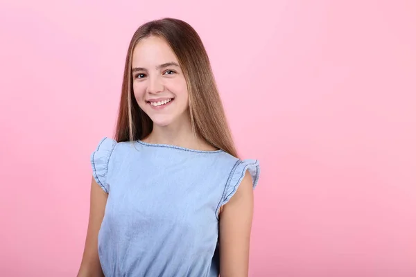 Jong meisje in blauwe jurk op roze achtergrond — Stockfoto