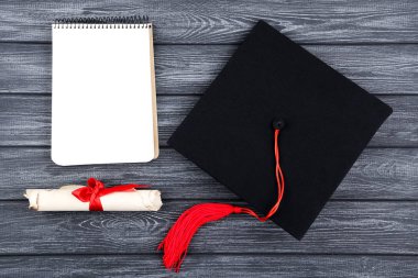 Siyah ahşap masa üzerinde diploma ve not defteri ile Mezuniyet kapağı
