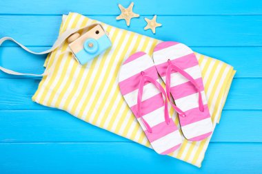 Mavi ahşap masa üzerinde denizyıldızları ve retro kamera ile parmak arası terlik çifti