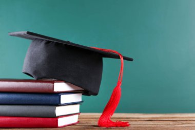 Yeşil tahta arka plan üzerinde kitap yığını ile Mezuniyet kapağı