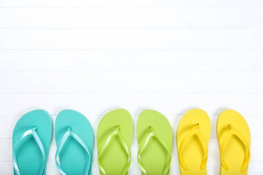 Beyaz ahşap masa üzerinde renkli parmak arası terlik çiftleri