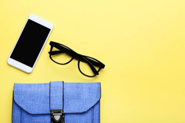 Sarı arka planda gözlük ve akıllı telefon ile Moda çanta