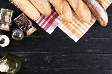 Siyah ahşap masa üzerinde peçete ve baharatile taze bagetler