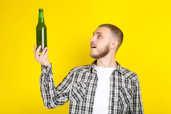 Ung man med flaska öl på gul bakgrund — Stockfoto
