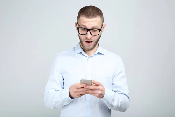 Joven en gafas con smartphone sobre fondo gris —  Fotos de Stock