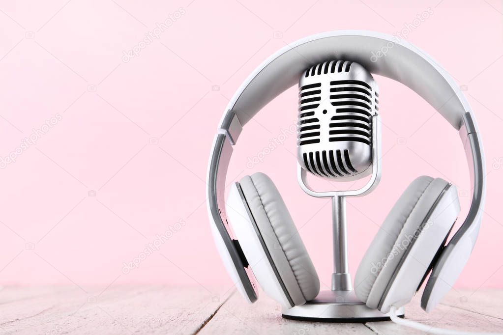 Vintage microphone with headphones on pink background