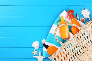 Deniz kabukları, çanta ve havlu mavi ahşap ile güneş kremi şişeler 