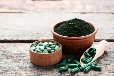 Spirulina toz ve tabletler üzerinde gri ahşap masa