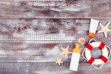 Ahşap masa üzerinde deniz kabukları ve lifebuoy ile güneş kremi şişeler