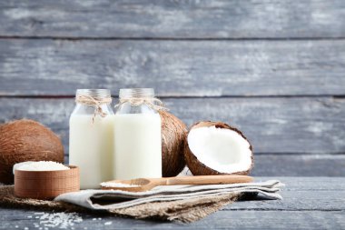 Gri ahşap masada pul ile şişelerde Hindistan cevizi sütü