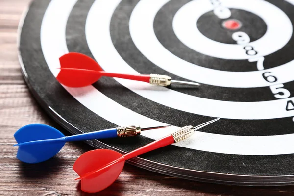 Dartboard com dardos na mesa de madeira marrom — Fotografia de Stock