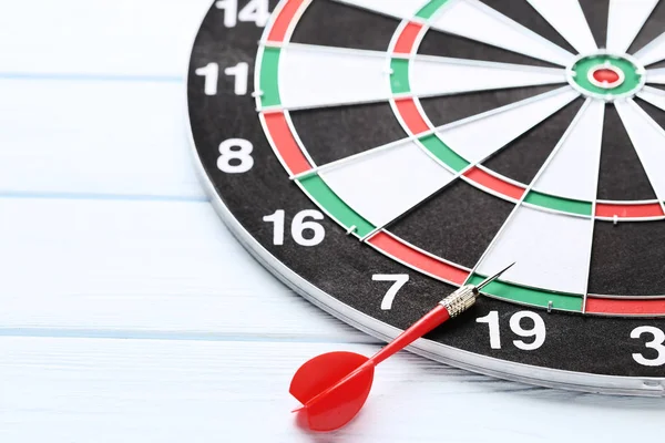 Dartboard com dardos na mesa de madeira — Fotografia de Stock