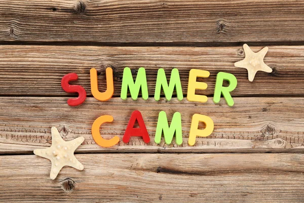 Texto Campamento de verano con estrellas de mar sobre mesa de madera marrón — Foto de Stock