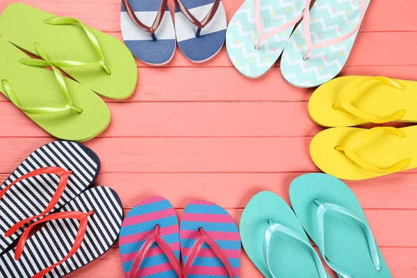 Pairs of colorful flip flops on wooden table — Stock Photo, Image