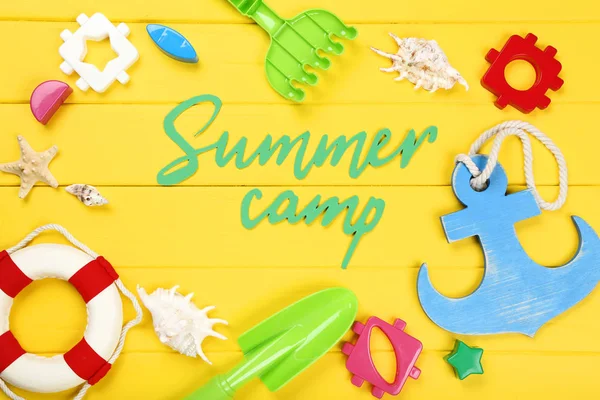 Paper text Summer camp with seashells and plastic toys on yellow — Stock Photo, Image