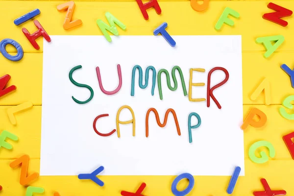Texto Campamento de verano con letras de plástico sobre mesa de madera amarilla — Foto de Stock