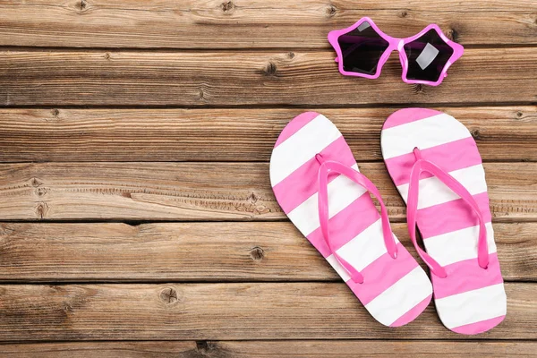 Pareja de chanclas con gafas de sol sobre mesa de madera marrón — Foto de Stock