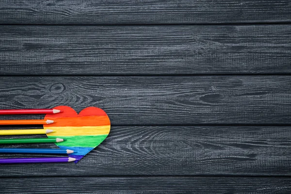 Regenbogen-Papierherz mit bunten Bleistiften auf Holztisch — Stockfoto