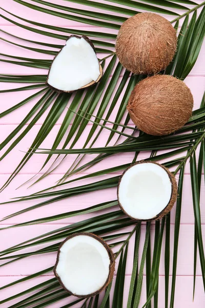 ピンクの木製テーブルの上の手のひらで熟したココナッツの葉します。 — ストック写真