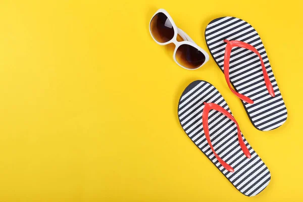 Pair of flip flops with sunglasses on yellow background — Stock Photo, Image