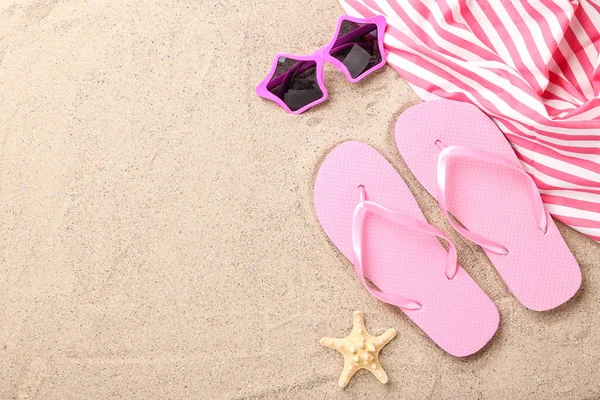Par de chinelos com estrelas do mar e óculos de sol na areia da praia — Fotografia de Stock