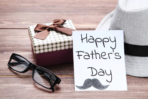 Text Happy Fathers Day with glasses, gift box and hat on wooden — Stock Photo, Image