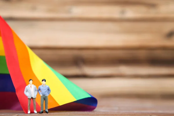 Miniatuur mensen met regenboog vlag op bruin houten tafel — Stockfoto