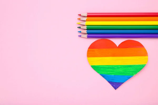 Regenboog papier hart met kleurrijke potloden op roze achtergrond — Stockfoto