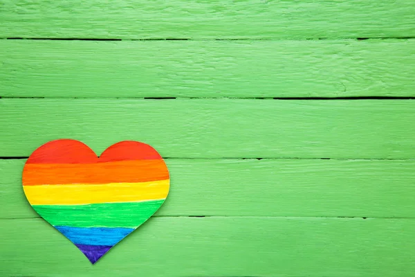 Herz aus Regenbogenpapier auf grünem Holztisch — Stockfoto