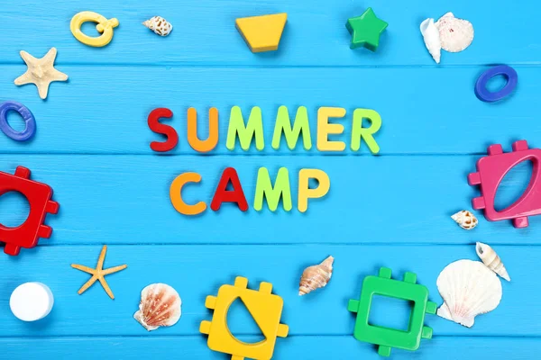 Text Summer camp with seashells and plastic toys on blue wooden — Stock Photo, Image