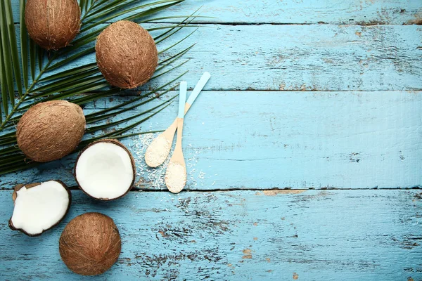 Cocos maduros con hojuelas en cucharas y hojas de palma sobre lana azul — Foto de Stock