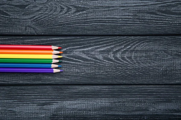 Regenboog potloden op zwarte houten tafel — Stockfoto