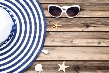 Kahverengi ahşap masa üzerinde deniz kabukları ve güneş gözlüğü ile Plaj şapkası