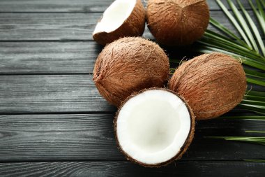 Olgunlaşmış hindistancevizi palmiye ile yapraklar üzerinde siyah ahşap masa