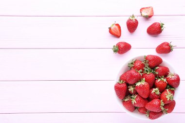 Pembe ahşap masada kase taze çilek