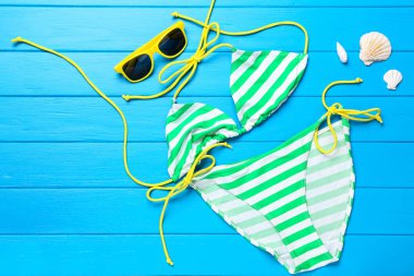 Mavi ahşap ta üzerinde deniz kabukları ve güneş gözlüğü ile Moda mayo