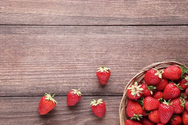 Kahverengi ahşap masa üzerinde sepet taze çilek