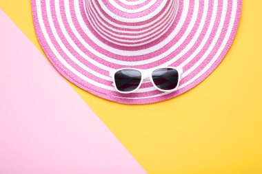Renkli arka planda güneş gözlüğü ile Plaj şapkası