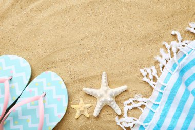 Plaj kumu üzerinde denizyıldızları ve havlu ile Flip flop
