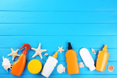 Mavi ahşap masa üzerinde deniz kabukları ile güneş kremi şişeleri