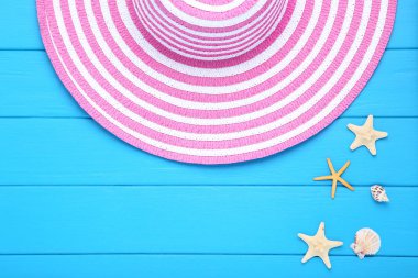 Mavi ahşap masa üzerinde deniz kabukları ile Moda şapka