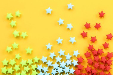 Sarı arka planda renkli kağıt yıldızları